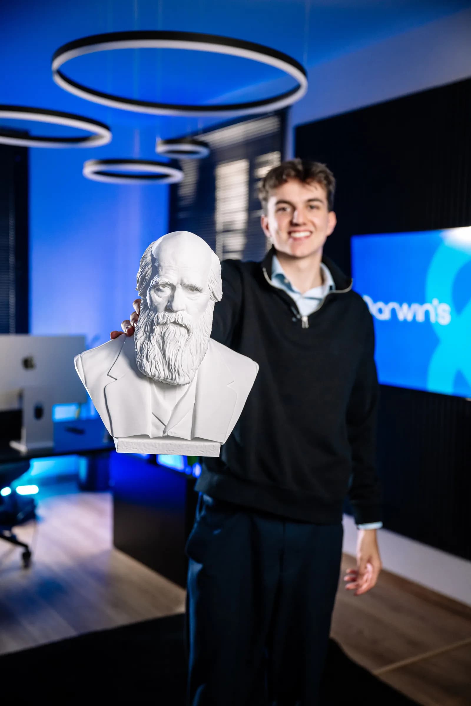 Leon Dapoz, fondatore di darwin's, tiene verso la camera un busto di Charles Darwin nell'ufficio di Bressanone